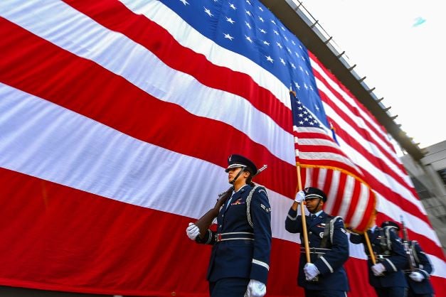 Soldiers walking in front of a large American flag