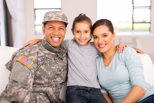 Man in military uniform sitting on a couch with his wife and daughter