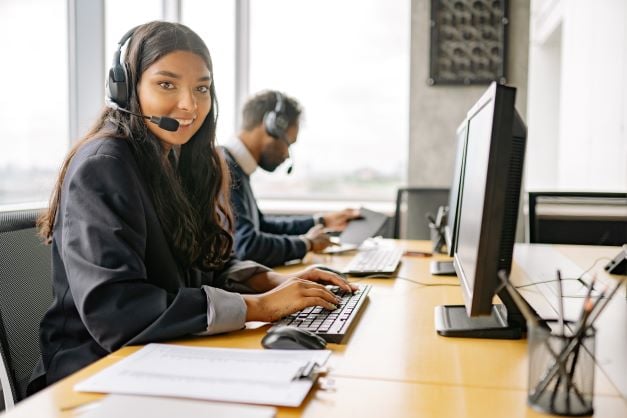 Woman wearing a headset while typing on a computer Woman wearing a headset while typing on a computer